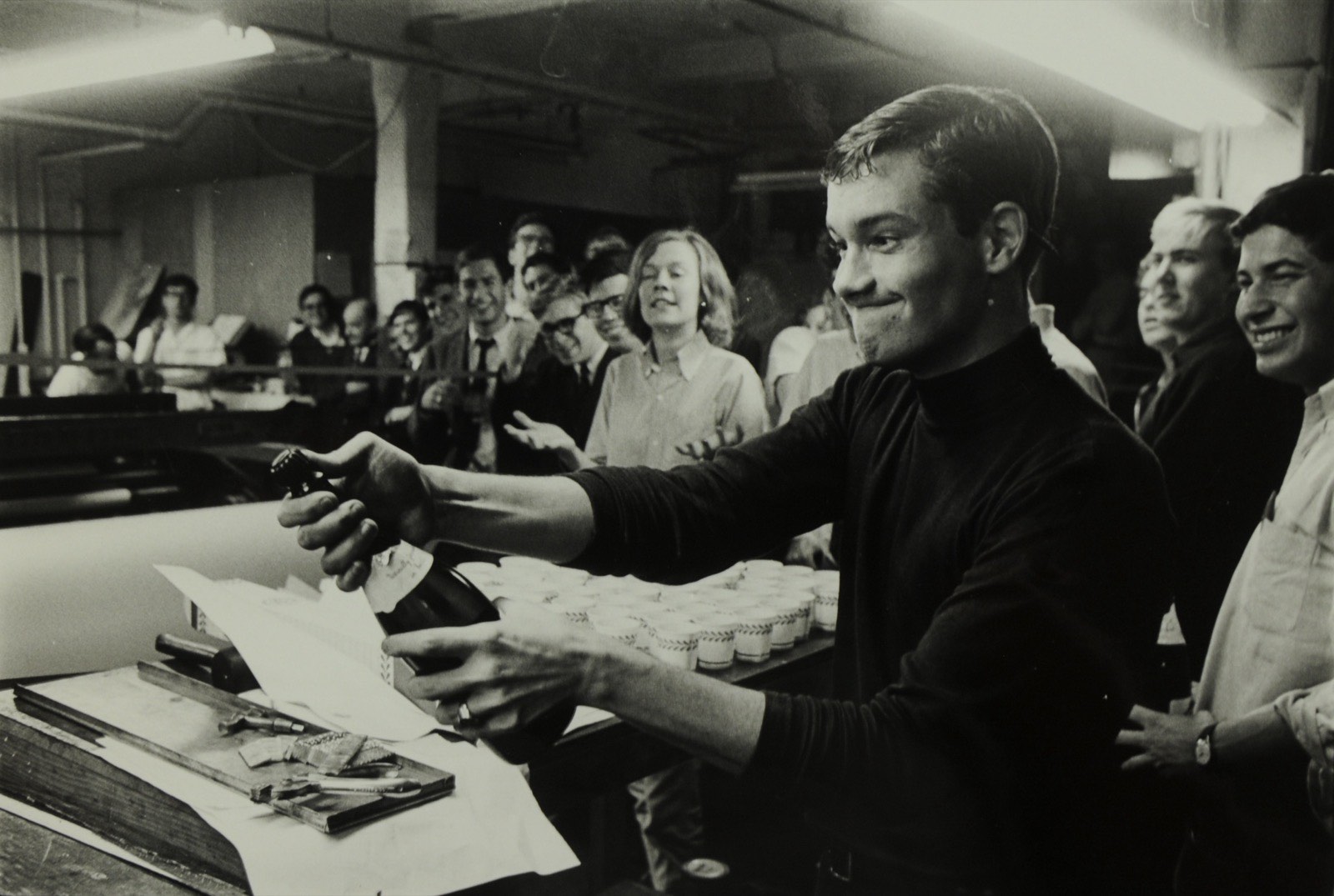 Crimson editors crowded around a bottle of champagne in the press room, December 1966